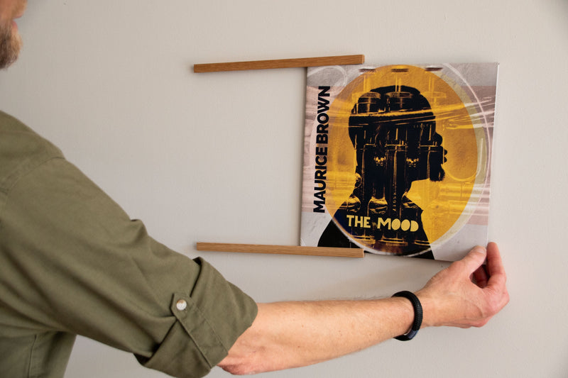 Platenliefhebber plaatst een lp-hoes in het eikenhouten Display SINGLE wandrek voor vinyl