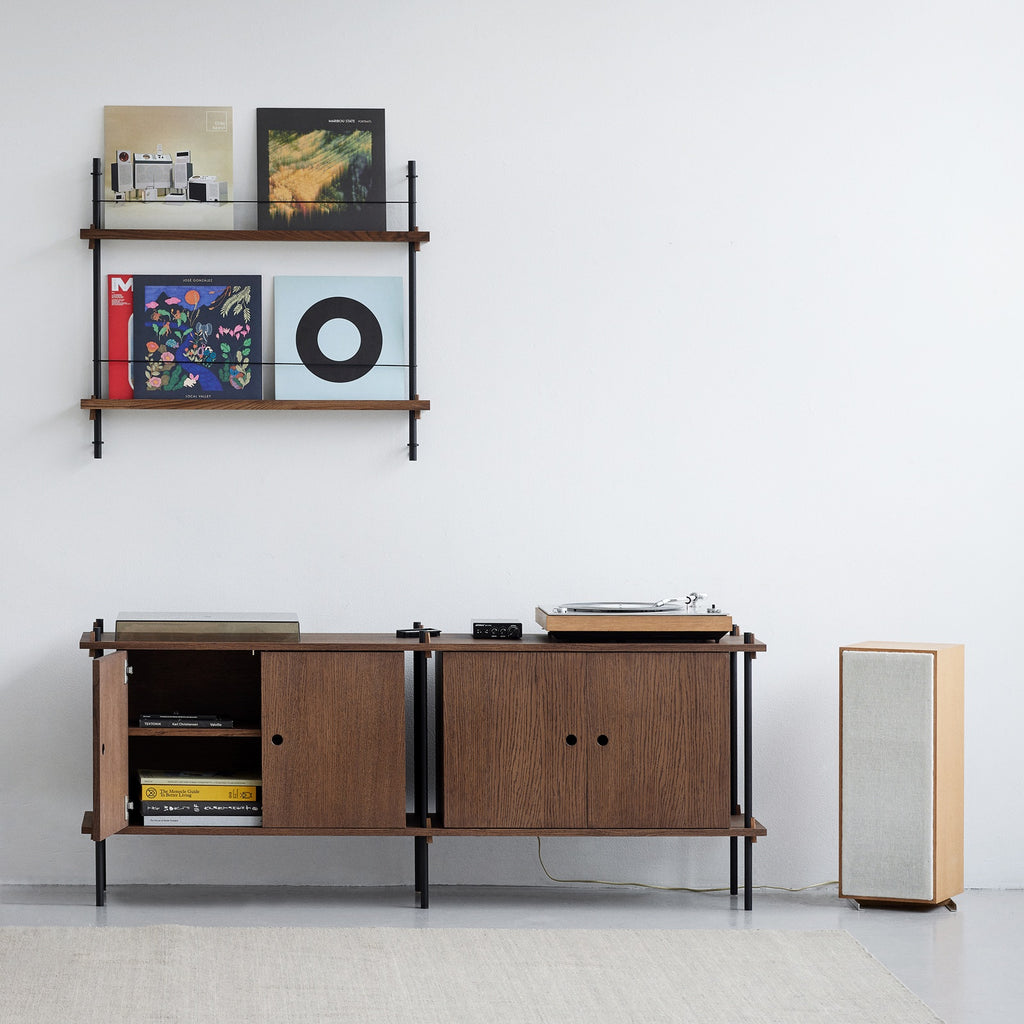 MOEBE platenrek aan de muur boven een modulair audiomeubel met platenspeler en luidspreker