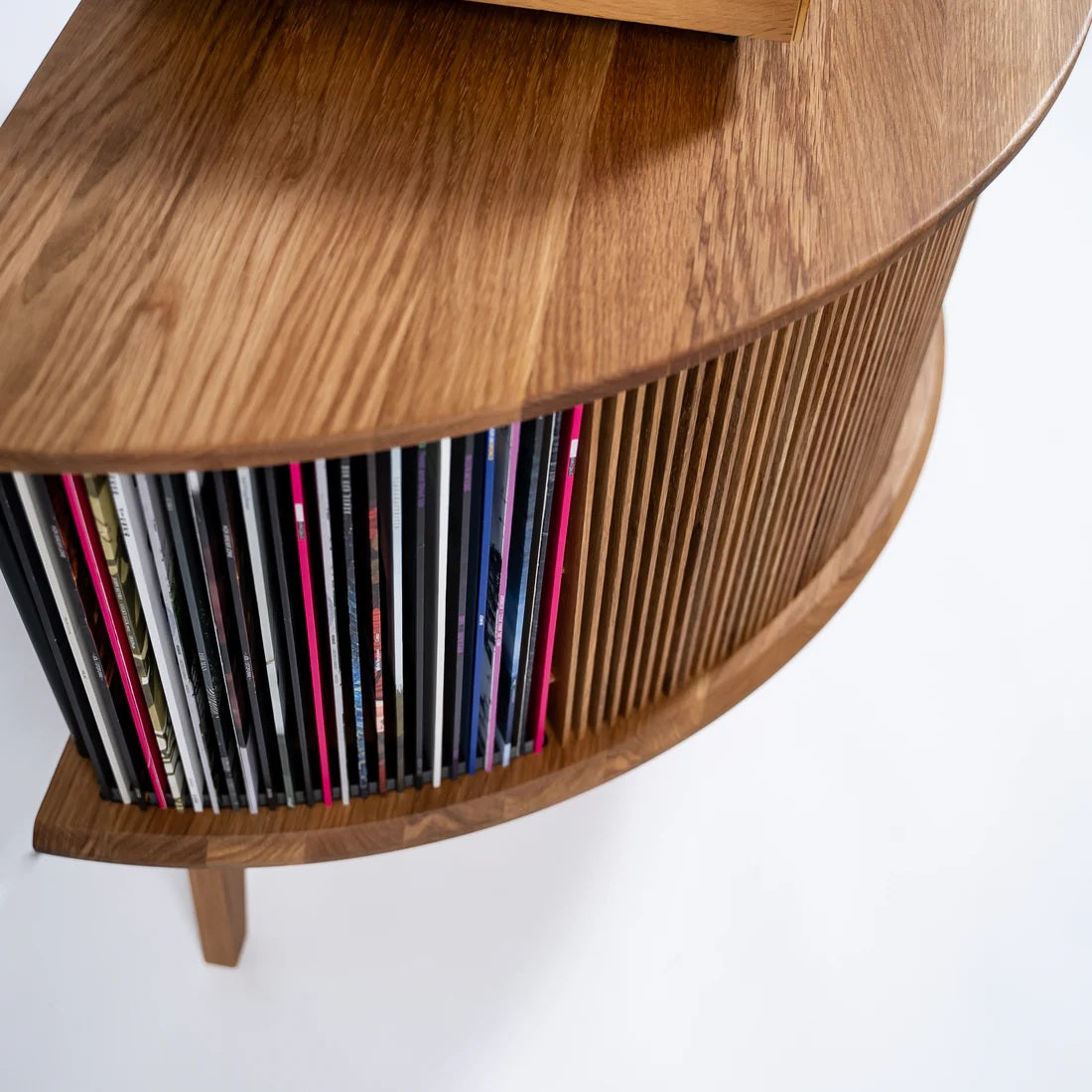 Schuin vooraanzicht van het gebogen Display LUNA vinyl display meubel met overzichtelijk opgeborgen platen