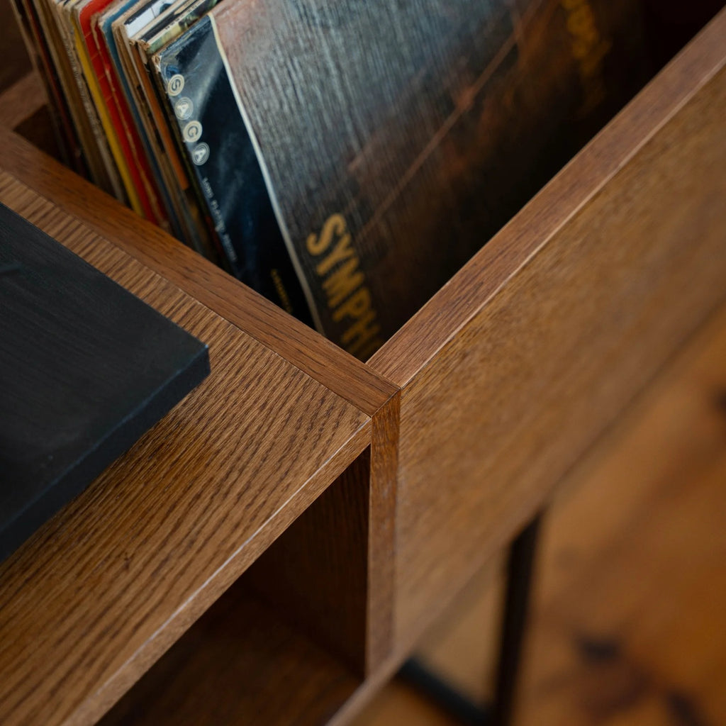 Bovenaanzicht van vinylplaten in de houten platenbak naast de platenspeler van de PLAY platenkast