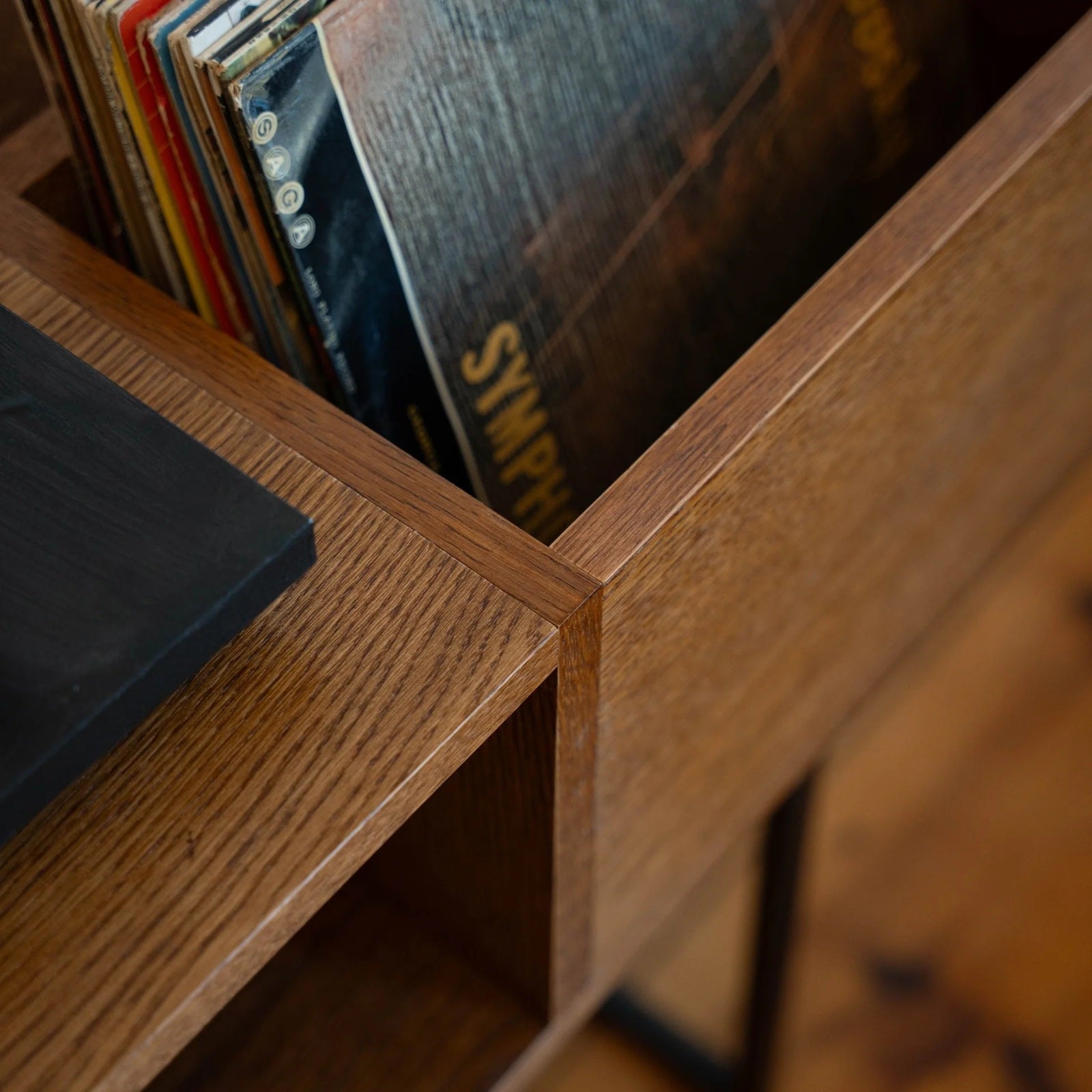 Bovenaanzicht van vinylplaten in de houten platenbak naast de platenspeler van de PLAY platenkast