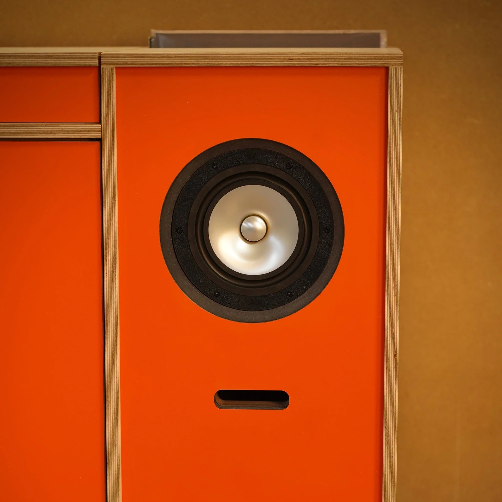 Detail van de ingebouwde full-range luidspreker in het oranje front van het Plyphonic Model B audiomeubel