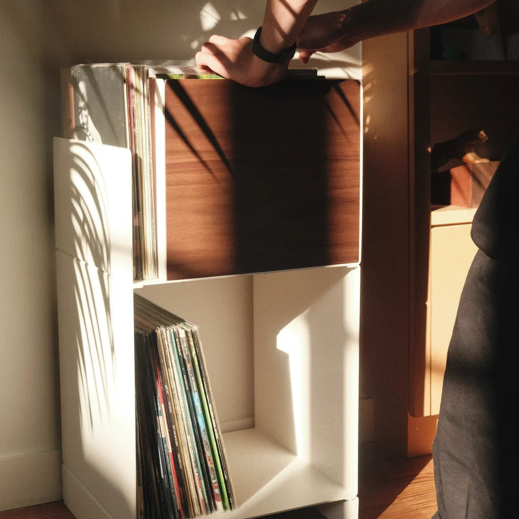 Witte LOIA Le Digger vinyl opslag met walnoten platenbak terwijl iemand door de LP-collectie bladert