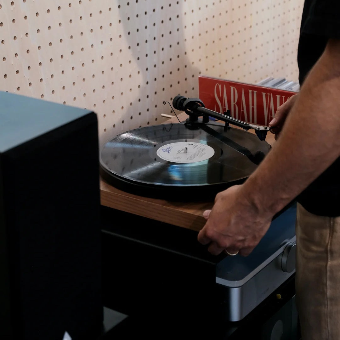 Vinylliefhebber bedient de platenspeler op het LOIA Le Meuble Digger meubel voor hifi en vinyl