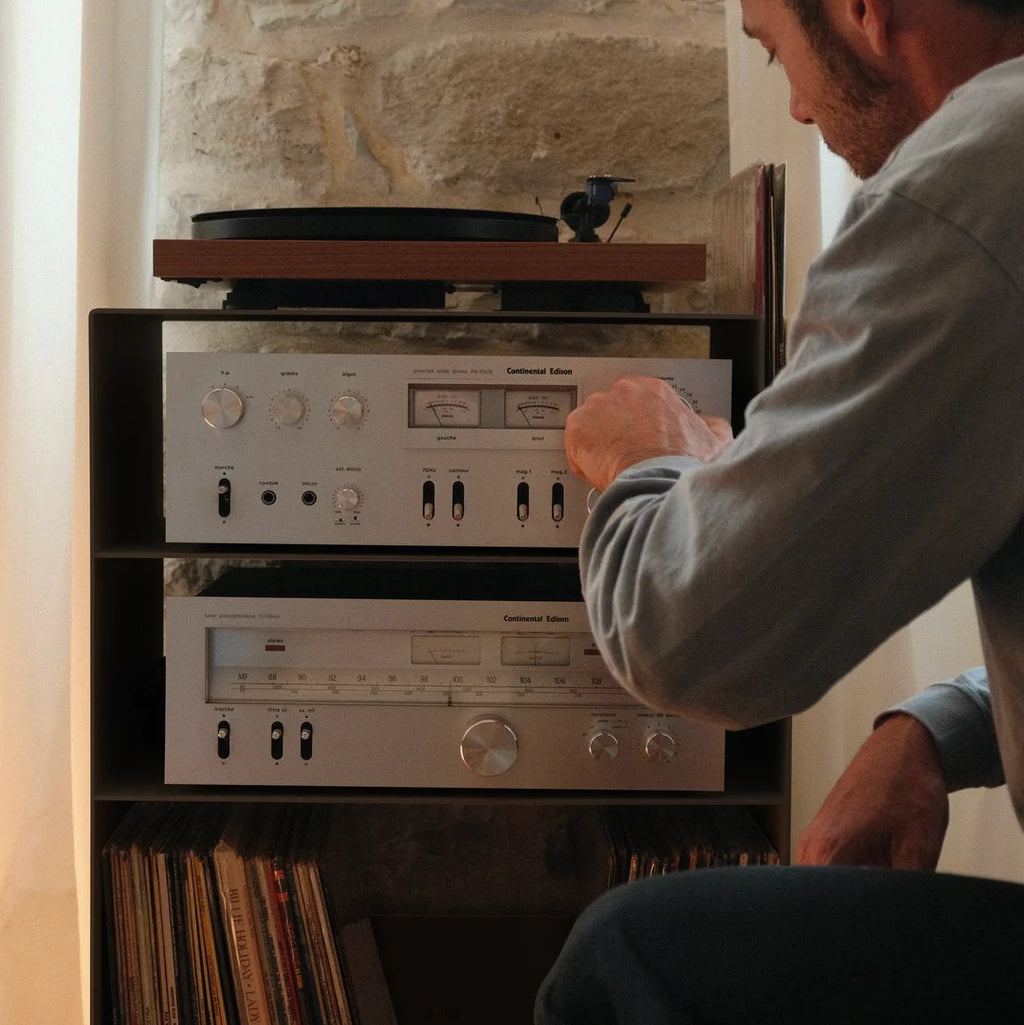 Detail van een muziekliefhebber die de versterker bedient in de LOIA La Console Acier hifi-kast