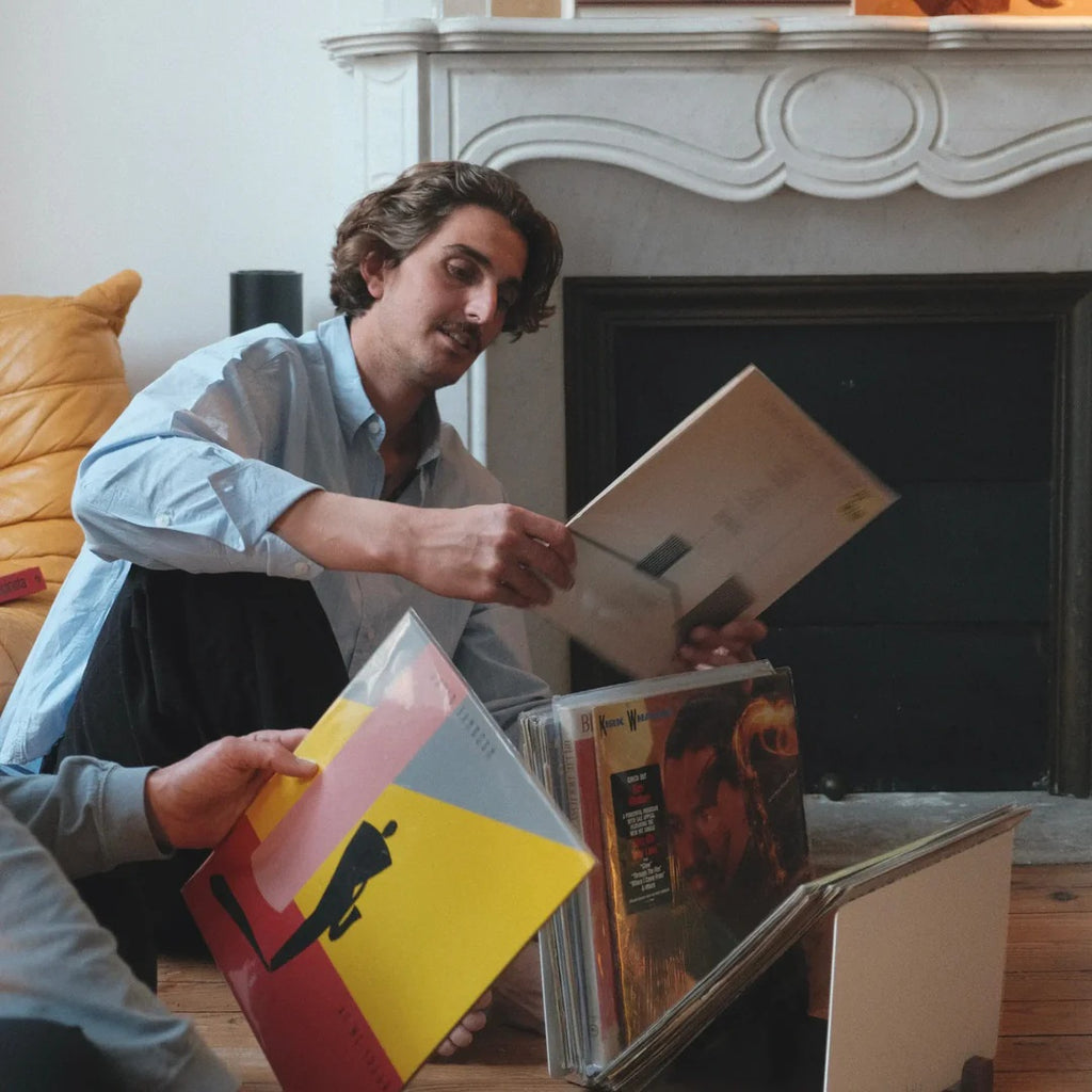 Vinylliefhebber kiest een lp uit de LOIA vinyl opslag in een sfeervolle woonkamer