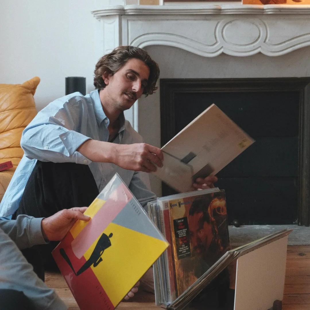Vinylliefhebber kiest een lp uit de LOIA vinyl opslag in een sfeervolle woonkamer