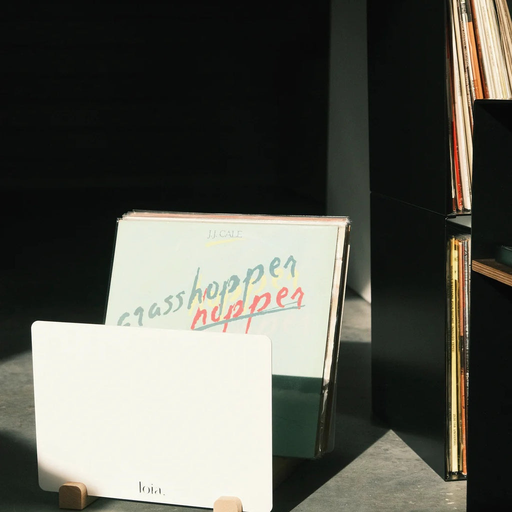 Witte LOIA vinyl opslag met beukenhouten details naast een zwarte platenkast met lp’s